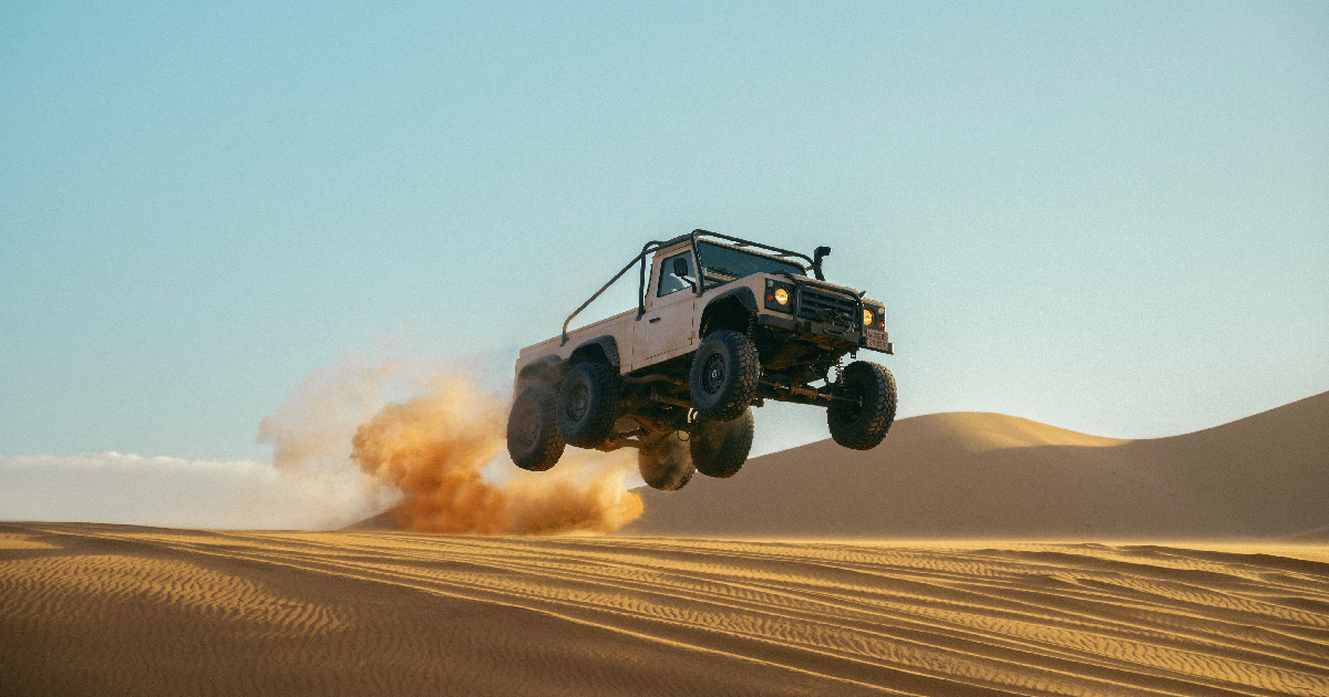 una jeep a 6 ruote vola sopra la sabbia nel trailer di matchbox - nerdface
