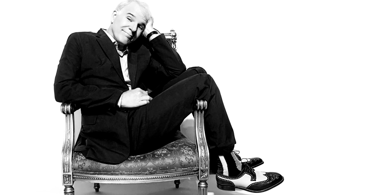 steve martin è seduto su una sedia con le gambe poggiate penzoloni sui reggigomiti - nerdface