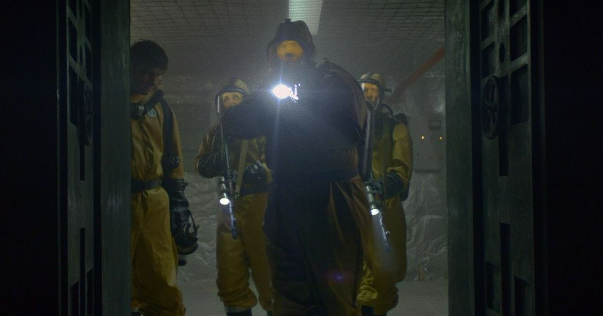 un gruppo di scienziati in tuta antiradiazioni gialla entra in un hangar - nerdface